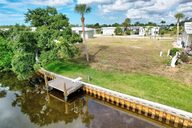a view of swimming pool with lawn chairs plants and lake view