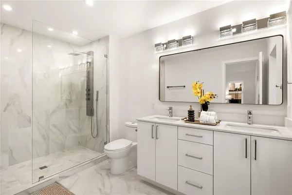 a bathroom with a toilet a sink a glass door a shower a mirror and vanity