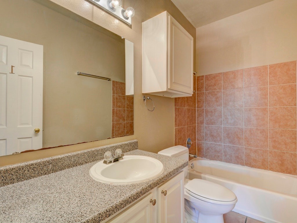 2502 Leon Street, Unit 102 Austin, TX 78705 - Photo 9 of 14 a bathroom with a granite countertop toilet a sink and a bathtub