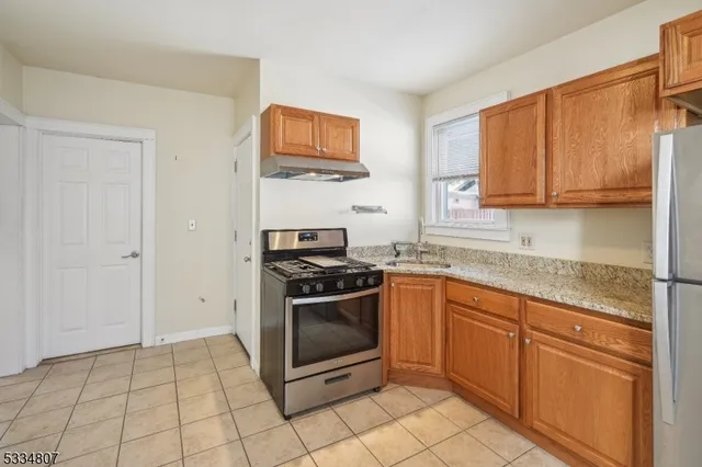 a kitchen with granite countertop a stove top oven cabinetry a sink and a window