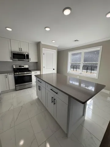 a large kitchen with stainless steel appliances kitchen island granite countertop a sink and cabinets