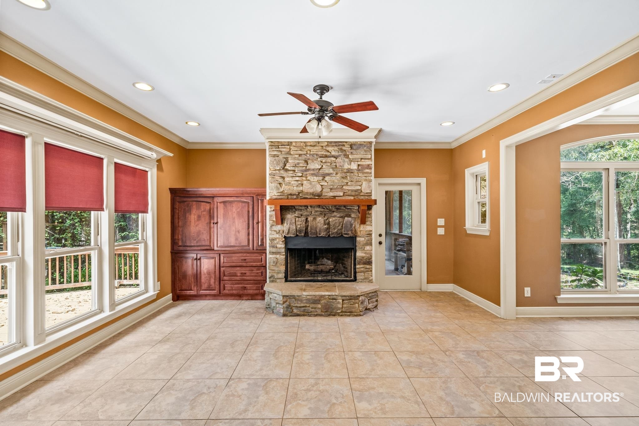 8321 Dixon Road Bay Minette, AL 36507 - Photo 29 of 79 Unfurnished living room featuring ceiling fan, light tile patterned floors, a stone fireplace, and crown molding