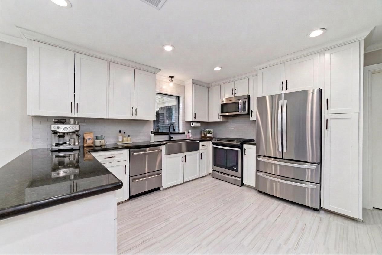 10607 Chimney Rock Road Houston, TX 77096 - Photo 12 of 35 This is a kitchen that actually works the way you need it to. Ceiling-height custom wood cabinets with crown molding give you real storage, not wasted space, and everything is finished clean with recessed lighting and task light right where you need it. Gas cooking, double drawer dishwasher, apron front farm sink with touchless faucet, true vent, and a full setup that handles real meals, not just takeout… plus a deep pantry and more storage than you’ll probably ever fill.
