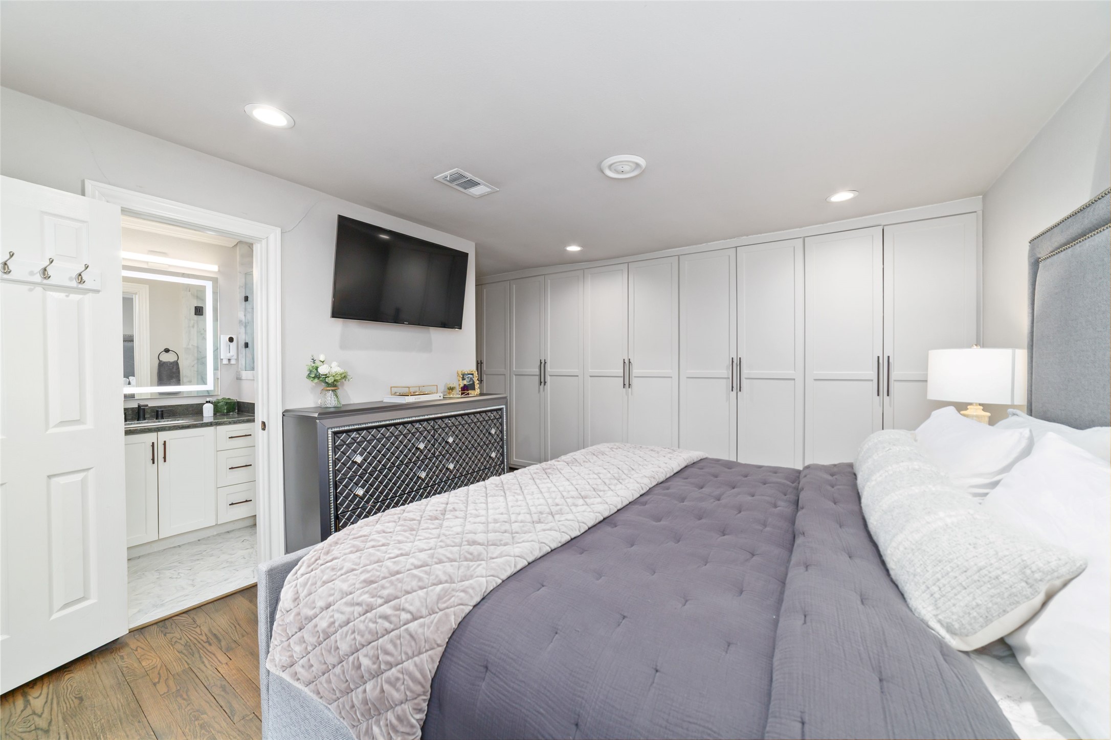 10607 Chimney Rock Road Houston, TX 77096 - Photo 24 of 35 Primary is quiet and tucked away, with a full wall of built-in armoires for both hanging and shelving. Custom shade keeps it calm and private when you want it. En suite bath sits right off, so everything flows easily.