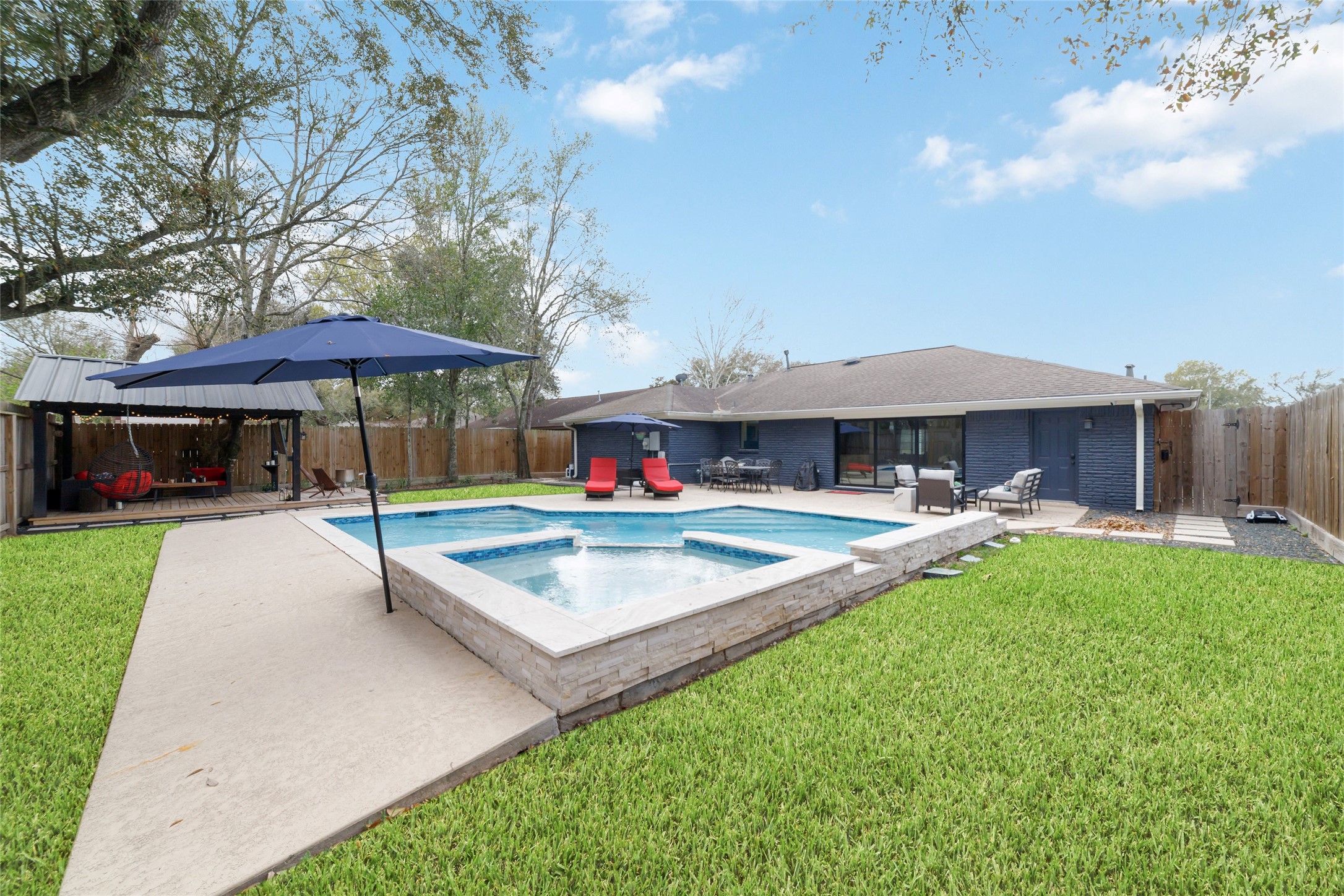 10607 Chimney Rock Road Houston, TX 77096 - Photo 3 of 35 Heated saltwater pool and spa with enough yard left over to actually use. Privacy fencing, accent rock, concrete steps, and a waterfall wall that gives it a finished feel. Dogs run, people spread out, and it never feels tight… you get both, which is rare.