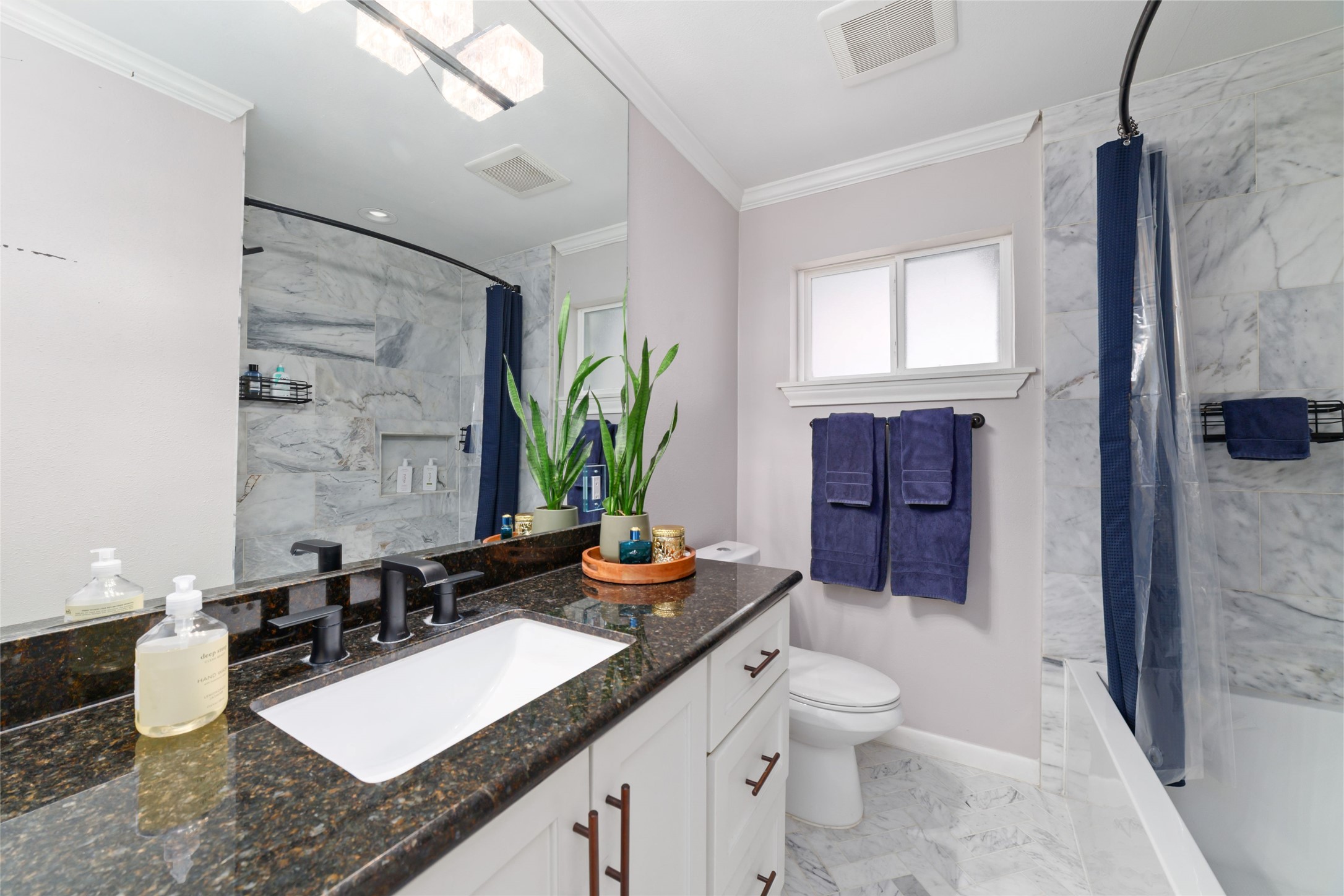 10607 Chimney Rock Road Houston, TX 77096 - Photo 31 of 35 Guest bath with good storage, ample counter space, and a tub/shower combo finished in marble tile. Built-in rod and clean layout make it easy for everyday use. It’s simple, functional, and consistent with the rest of the home.