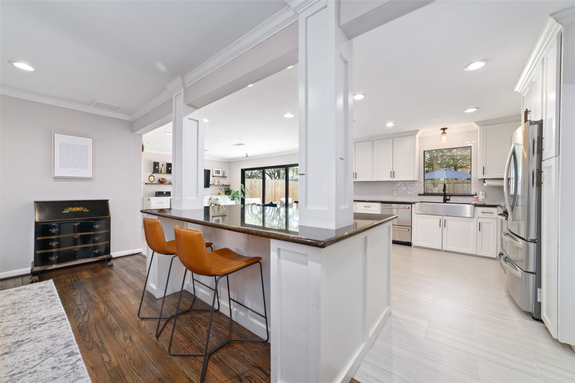 10607 Chimney Rock Road Houston, TX 77096 - Photo 10 of 35 The center of the home where everyone ends up, and this one actually supports it. Nearly eight-foot island with depth, seating for three, and cut-ins so you’re not knees-to-cabinet… topped in black granite that holds up to real cooking, color, and spice. Custom columns frame the space and keep everything connected, so from your seat you’re still part of the living room, the kitchen, and even the view out back.
