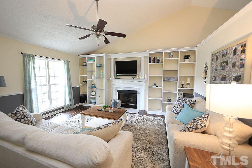 409 Flagg Road Holly Springs, NC 27540 - Photo 2 of 14 Family room features vaulted ceiling, gas fireplace, laminate flooring and a ceiling fan.