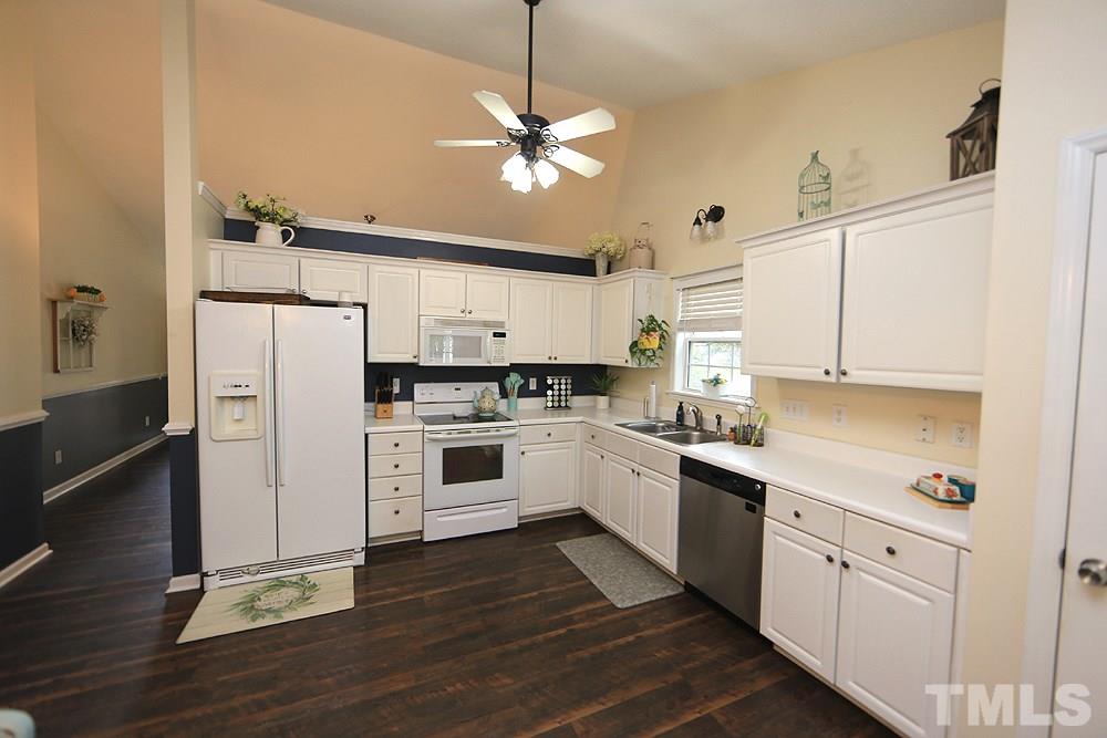 409 Flagg Road Holly Springs, NC 27540 - Photo 4 of 14 The kitchen features white cabinets, ceiling fan and laminate flooring.