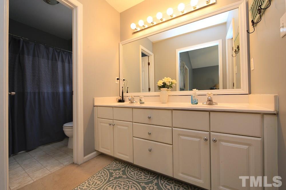 409 Flagg Road Holly Springs, NC 27540 - Photo 7 of 14 Master bath features white cabinets with double vanity and picture mirror.