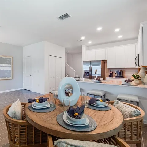 a kitchen with a dining table chairs and refrigerator
