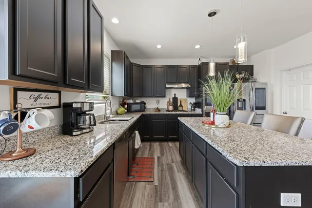a kitchen with granite countertop kitchen island stainless steel appliances a sink stove and cabinets