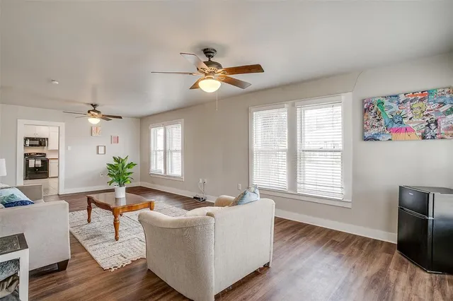 a living room with couches and a dining table with wooden floor