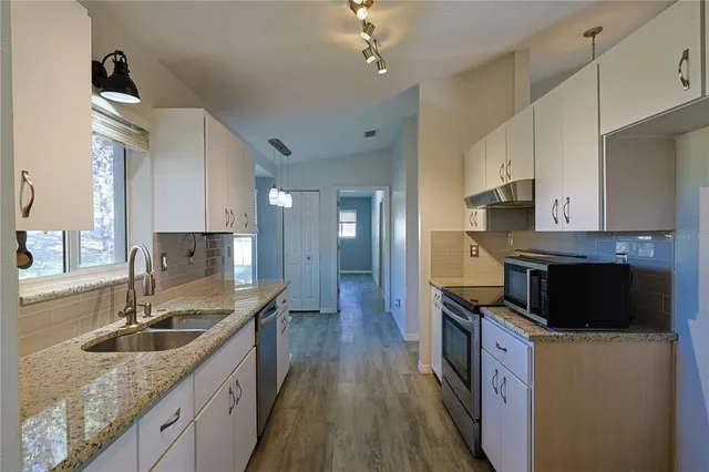 a kitchen with kitchen island granite countertop a sink a counter space appliances and cabinets