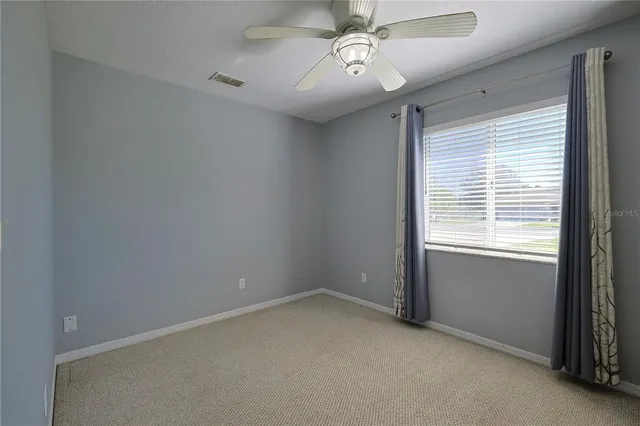 en empty room with windows and ceiling fan