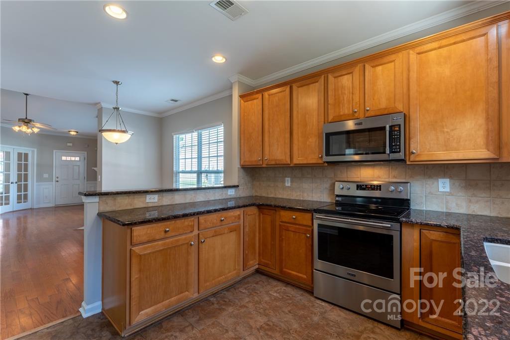 261 Sand Paver Way Fort Mill, SC 29708 - Photo 11 of 45 a kitchen with stainless steel appliances granite countertop wooden cabinets and a stove top oven