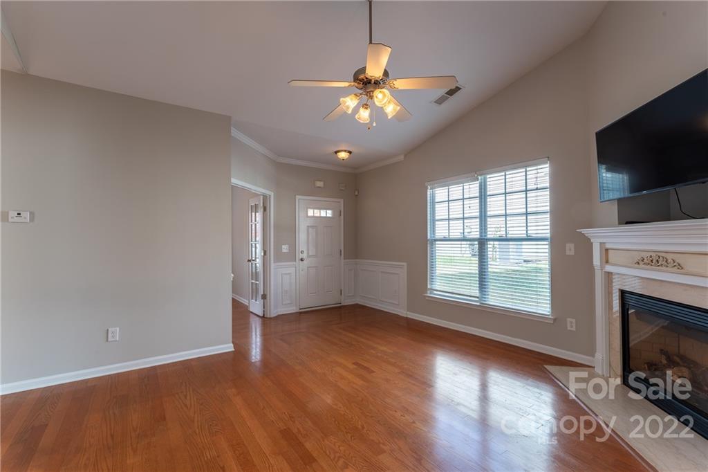 261 Sand Paver Way Fort Mill, SC 29708 - Photo 8 of 45 an empty room with wooden floor a chandelier fan and a fireplace
