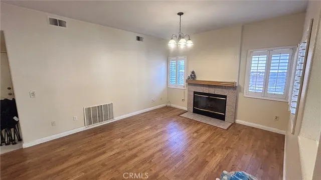 an empty room with wooden floor fireplace cabinet and windows
