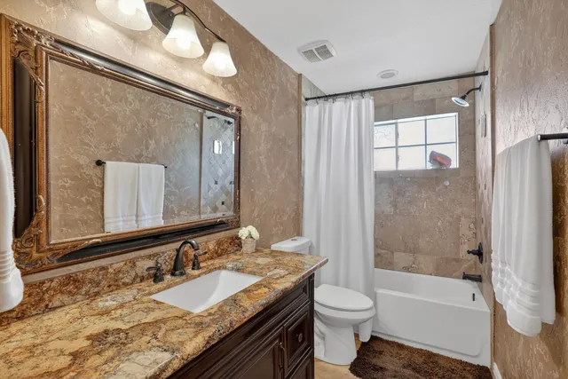 a bathroom with a granite countertop sink toilet and shower