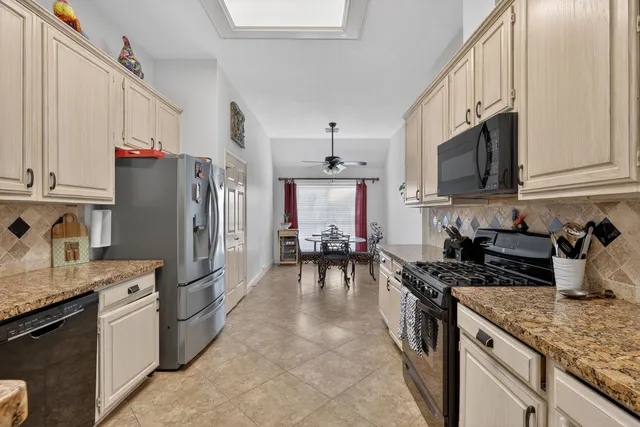 a kitchen with granite countertop a refrigerator stove and sink
