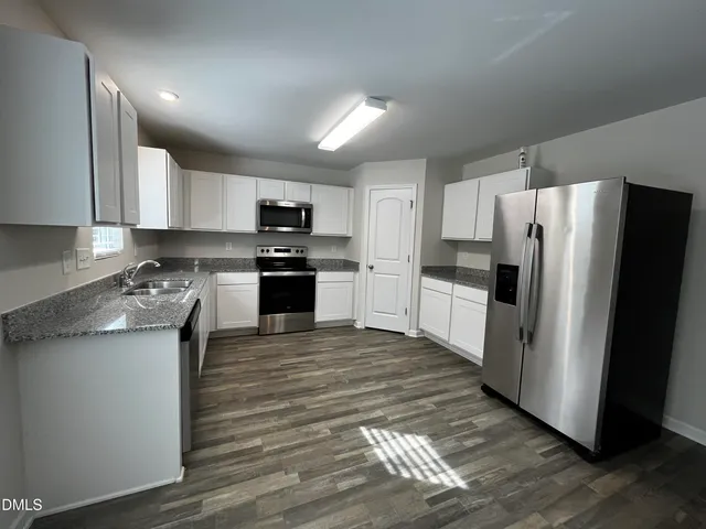 a kitchen with stainless steel appliances granite countertop a refrigerator stove microwave and sink