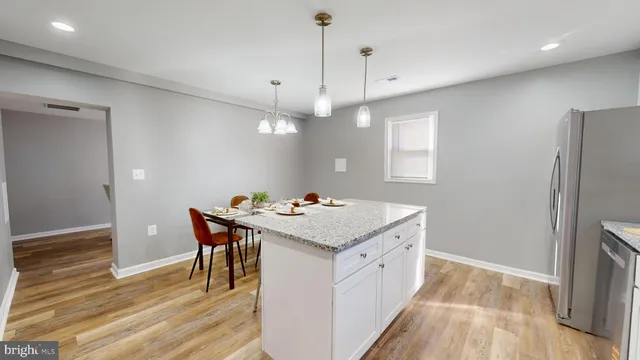 a kitchen with a stove a refrigerator a sink dishwasher with a dining table and chairs with wooden floor