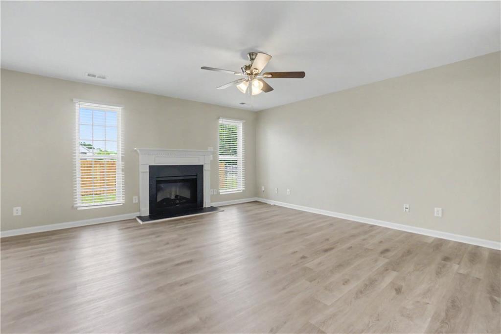 375 Walton View Fairburn, GA 30213 - Photo 11 of 38 an empty room with wooden floor a ceiling fan and windows
