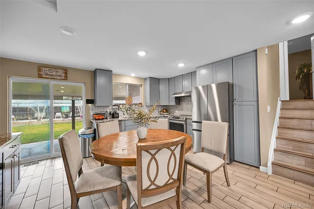 a dining room with stainless steel appliances a dining table and chairs