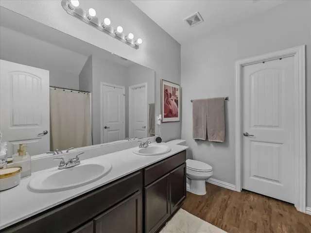 a bathroom with a double vanity sink mirror and toilet