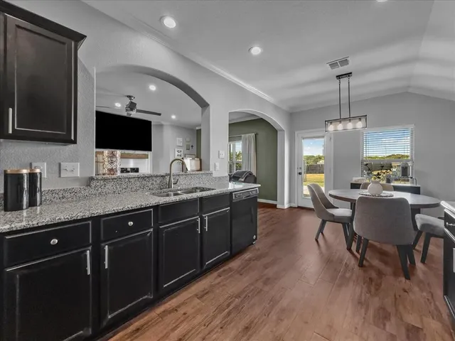 a kitchen with a kitchen island hardwood floor sink stove dining table and chairs