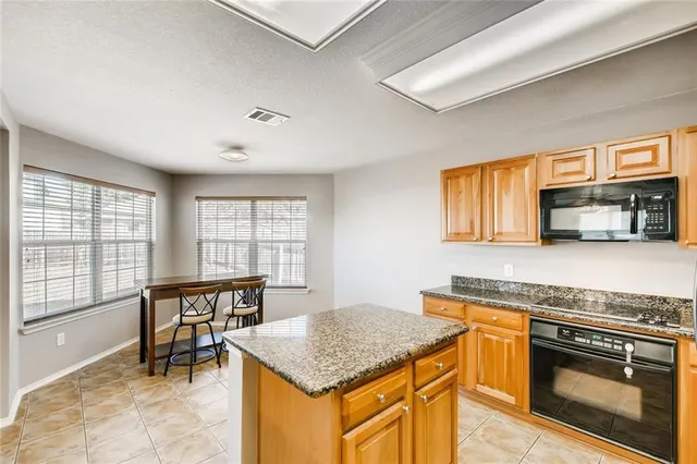 a kitchen with stainless steel appliances granite countertop a stove top oven a sink a dining table and chairs with wooden floor