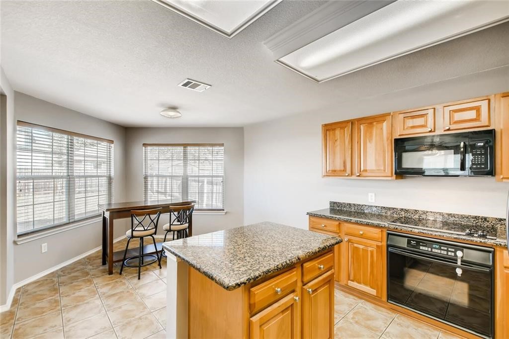 1149 Apollo Circle Round Rock, TX 78664 - Photo 7 of 14 a kitchen with stainless steel appliances granite countertop a stove top oven a sink a dining table and chairs with wooden floor