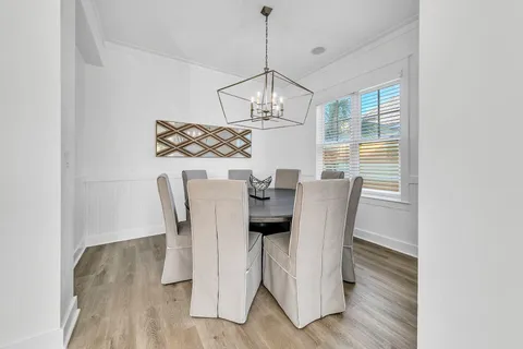 a dining room with furniture a chandelier and wooden floor