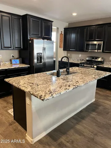 a kitchen with kitchen island granite countertop a sink stove and refrigerator