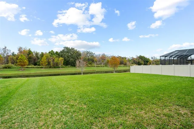 a view of a green field with trees in the background