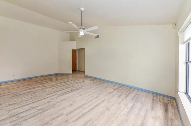 a view of empty room with wooden floor and fan