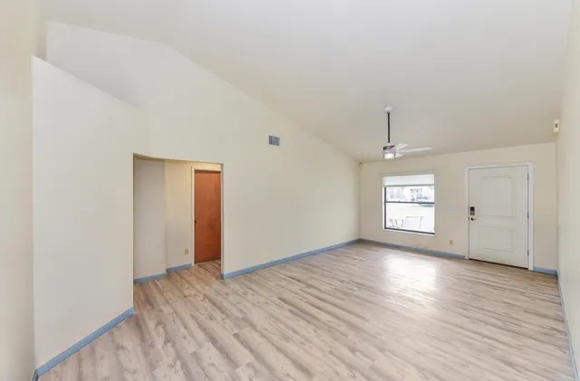 a view of an empty room with wooden floor and a window