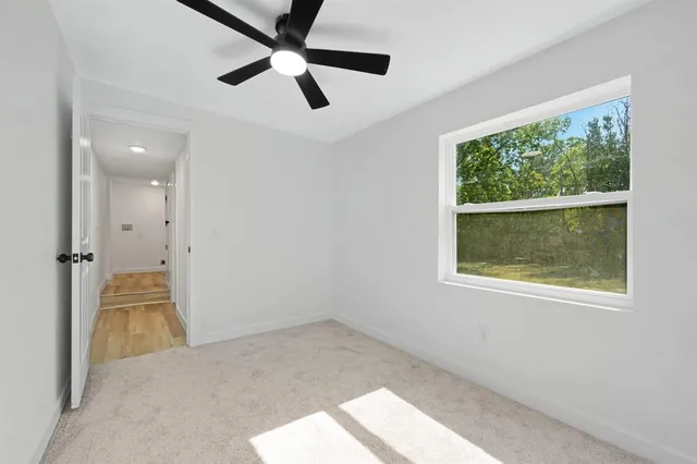 an empty room with a ceiling fan and windows