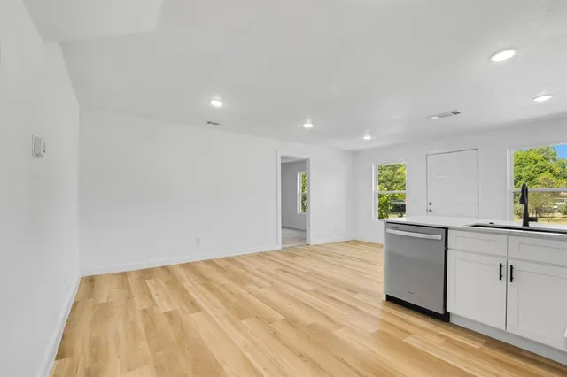 a view of a kitchen with a sink and dishwasher a stove top oven with wooden floor