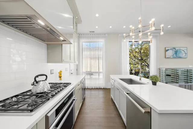 a kitchen with stainless steel appliances white cabinets and a stove top oven