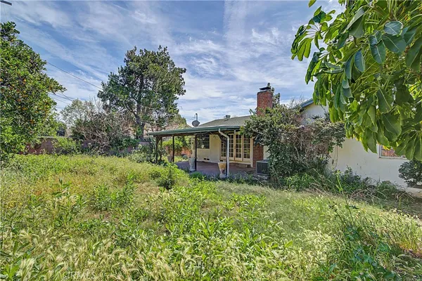 a backyard of a house with table and chairs and wooden fence
