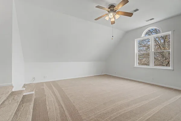 an empty room with a window and a ceiling fan