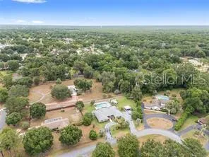 an aerial view of residential houses with outdoor space and trees