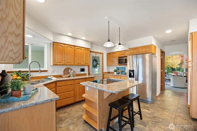 a kitchen with stainless steel appliances kitchen island granite countertop a sink refrigerator and cabinets