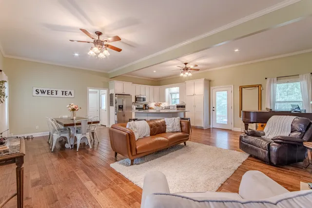 a living room with furniture kitchen view and a chandelier