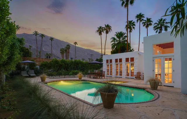 a view of swimming pool with outdoor seating and house in the background