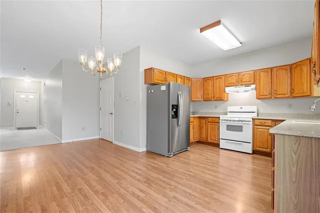 a kitchen with stainless steel appliances granite countertop a refrigerator a sink dishwasher a stove with wooden floor and cabinets