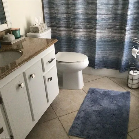 a bathroom with a granite countertop toilet sink and mirror