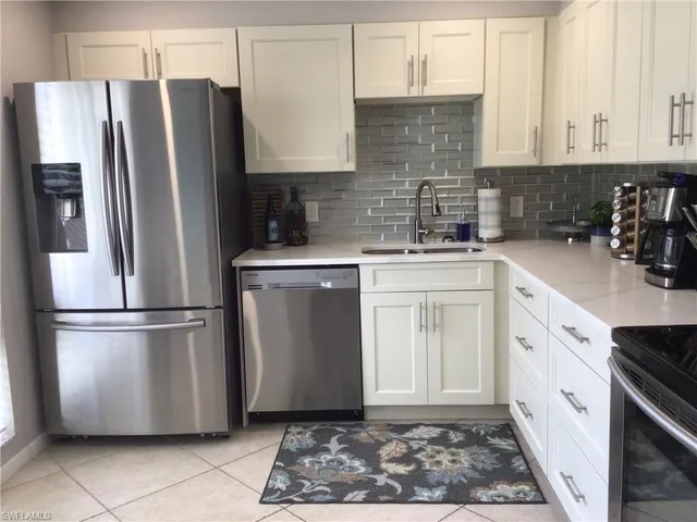 a kitchen with stainless steel appliances granite countertop a refrigerator a sink a stove and white cabinets