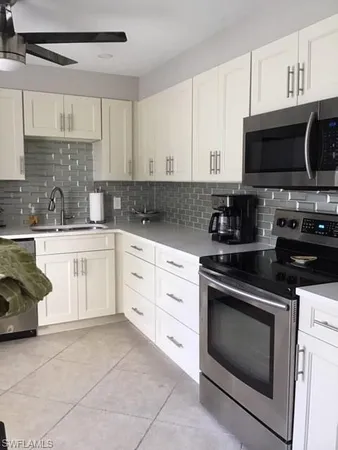 a kitchen with white cabinets appliances and a sink